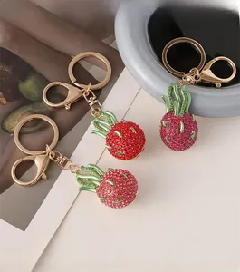 Close-up of sparkling rhinestone dragon fruit keychain with gold lobster clasp and green leaf