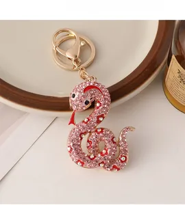Gros plan détaillé du porte-clés serpent doré serti de strass roses et fleurs émaillées rouges