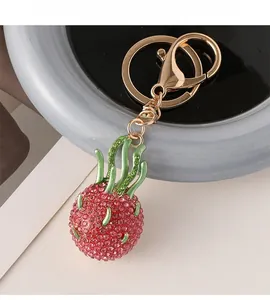 Macro view of creative dragon fruit keychain with red rhinestones and gold lobster clasp