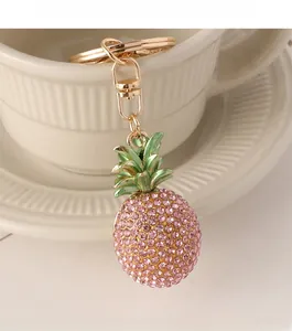 Detail of a sparkling diamond pineapple keychain hanging on a stylish yellow ceramic cup