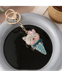 Macro shot of sparkling crystal cat ice cream keychain in gold with pink bow and blue stones