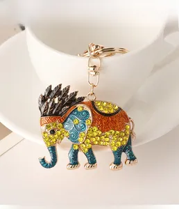 Detail of a golden elephant keychain with yellow rhinestones on a white coffee cup