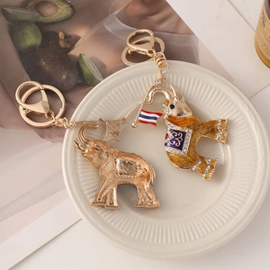 Thai style elephant keychain with gold glitter and white crystals on a white ceramic plate