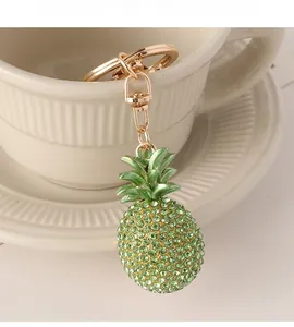 Detail of a sparkling green rhinestone pineapple keychain hanging on a white ceramic cup