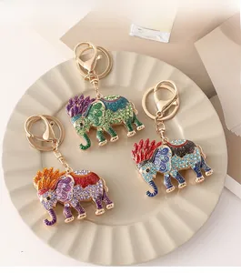Detailed view of three colorful elephant keychains with rhinestones on a ceramic tray