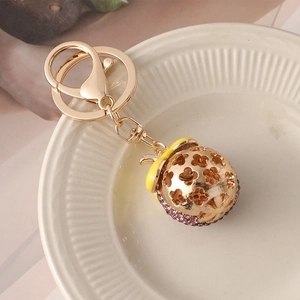 Golden mangosteen hollow ball keychain with purple rhinestones and yellow enamel detail