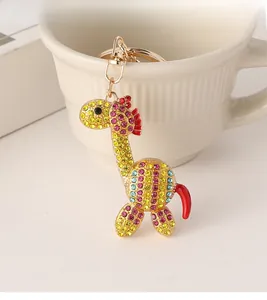 Dettaglio del portachiavi a giraffa con strass colorati appeso al bordo di una tazza bianca