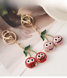 Detail view of sparkling rhinestone cherry keychains with red and pink enamel smiling faces