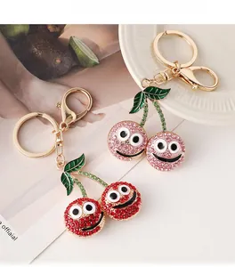 Detail of red and pink rhinestone cherry keychains with smiley faces and gold lobster clasp