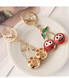 Detailed close-up of cherry keychains with red rhinestones and gold hollow metal design