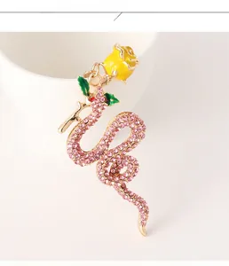 Close-up of golden snake keychain with pink crystals and a yellow rose flower detail