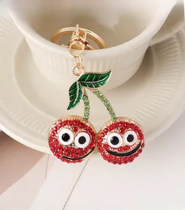Close-up of sparkling cherry keychain with red rhinestones and smiling face detail