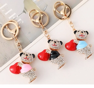 Detalle de tres llaveros de osos con diamantes de imitación en rosa, negro, azul y cierres oro