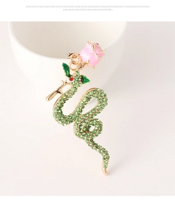 Detail of green crystal snake keychain with pink enamel rose on a white ceramic cup