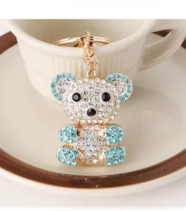 Close-up of golden bear keychain featuring inlaid blue and white crystals on metal