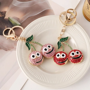 Creative sparkling cherry keychain with rhinestones and cartoon smiley face on white plate