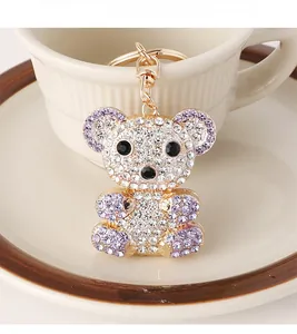 Close-up of sparkling rhinestone bear keychain on a white ceramic cup edge