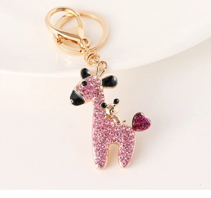 Detail of giraffe keychain featuring pink rhinestones and golden heart charm on white base
