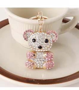 Close-up of a sparkling crystal-encrusted bear keychain on a white ceramic cup