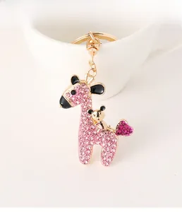 Macro shot of gold deer keychain with pink crystals and small bear on white cup