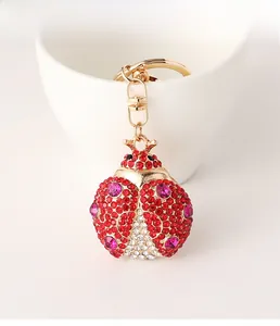 Close-up of a rhinestone beetle keychain with red crystals on a white ceramic background