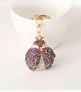 Close-up of a beetle keychain with purple rhinestones on a golden alloy metal frame