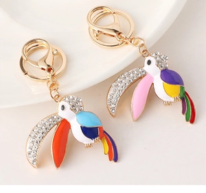 Détail de deux porte-clés toucan avec émail coloré et strass brillants sur fond blanc