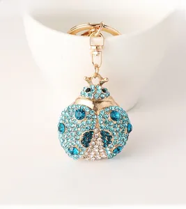 Macro detail of beetle keychain with blue rhinestones hanging on a white porcelain cup