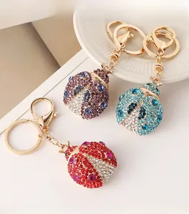 Detailed macro view of crystal-encrusted beetle keychains in red, purple, and blue colors