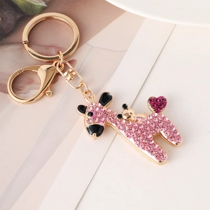 Cute golden giraffe keychain with pink rhinestones and heart detail on plain background
