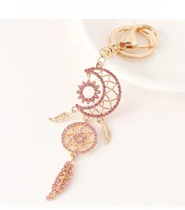Detailed view of moon dreamcatcher keychain with pink crystals and golden feathers