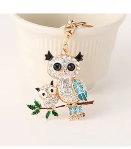Détail du porte-clés hibou avec strass bleus brillants et feuilles en émail vert