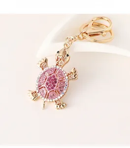 Detailed view of turtle keychain with pink rhinestones on a gold metal frame