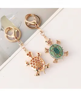 Close-up of golden turtle keychains featuring green and champagne rhinestones