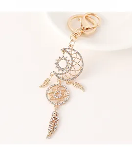 Detailed macro view of a golden dreamcatcher keychain with moon and feathers in rhinestones