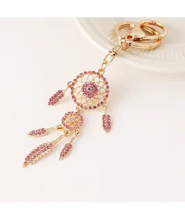 Detailed close-up of golden dreamcatcher keychain with pink crystals and feathers