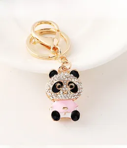 Close-up of cute panda keychain with white crystals and pink dress on gold-tone alloy