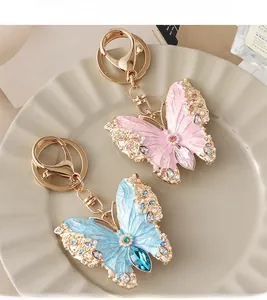 Detailed macro view of enamel butterfly keychains with pearls and crystals in a ceramic tray
