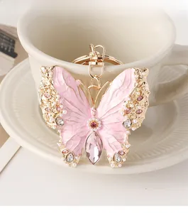 Detail of butterfly keychain with pink enamel, pearls and crystals on a coffee cup