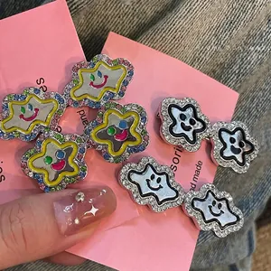 Colorful rhinestone cloud and star smiley face hair clips held against pink cardstock