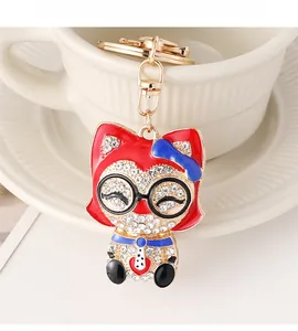 Détail du porte-clés chat en émail rouge et strass sur une tasse en céramique blanche