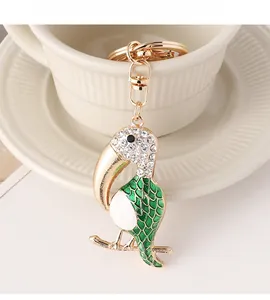 Close-up of a crystal-encrusted parrot keychain with green enamel detail on a ceramic cup