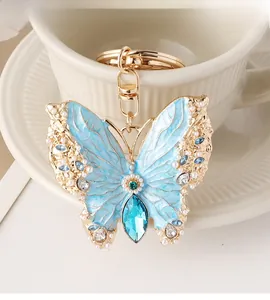 Detail of blue enamel butterfly keychain featuring pearls and crystals on a white cup