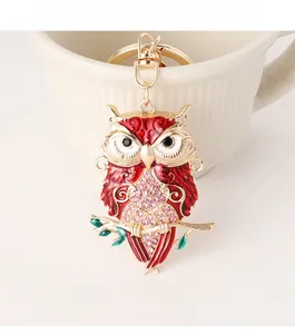 Close-up of owl keychain with red enamel, pink crystals, and a golden lobster clasp