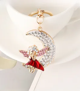 Dettaglio portachiavi luna e angelo dorato con strass scintillanti e ali rosa delicate