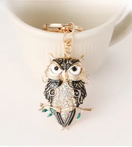 Close-up of golden owl keychain with sparkling rhinestones and green leaf detail