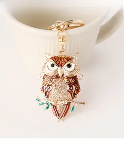 Macro detail of owl keychain with red enamel wings and rhinestones on a ceramic cup