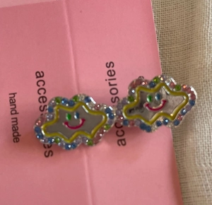 Close-up of handmade cloud-shaped hair clips with colorful rhinestones and smiley face