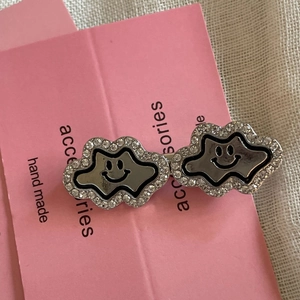 Detail of handmade cloud hair clips with sparkling rhinestones and black smiley faces