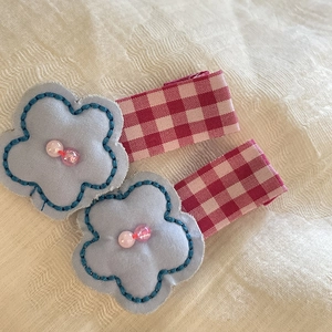Detail of blue floral hair clips with pink beads and red plaid ribbon wrapping